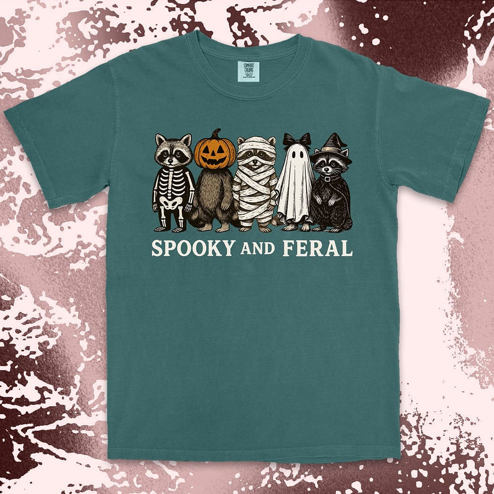 Comfort Color t-shirt with five raccoons in Halloween costumes (skeleton, pumpkin, mummy, ghost, witch) and text “Spooky and Feral.”