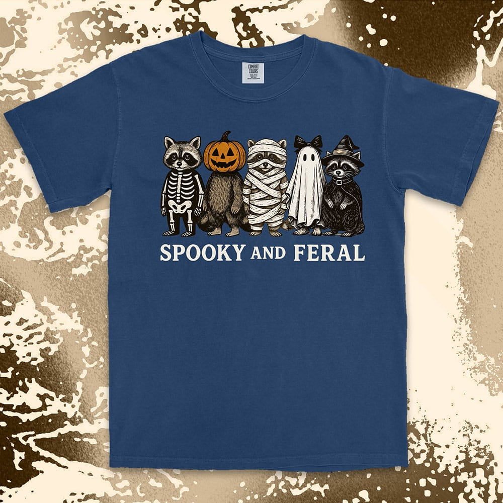 Comfort Color t-shirt with five raccoons in Halloween costumes (skeleton, pumpkin, mummy, ghost, witch) and text “Spooky and Feral.”