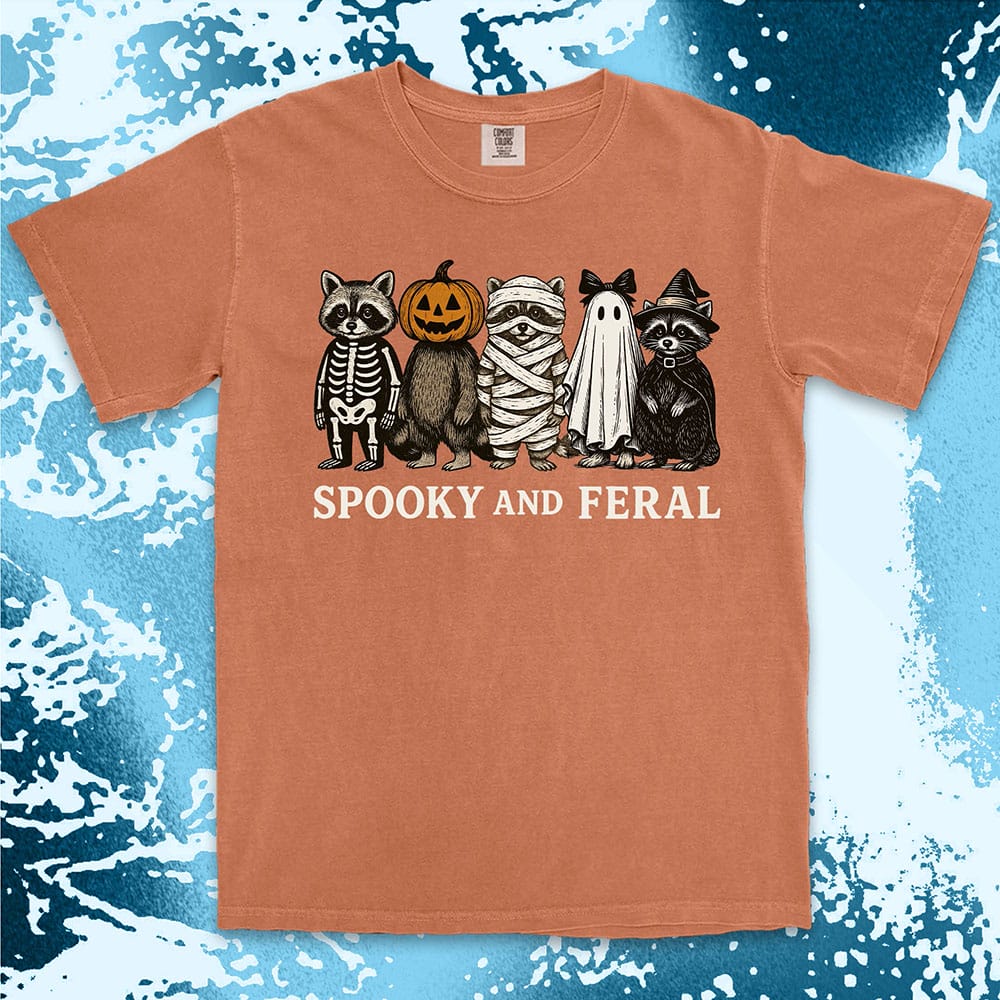 Comfort Color t-shirt with five raccoons in Halloween costumes (skeleton, pumpkin, mummy, ghost, witch) and text “Spooky and Feral.”