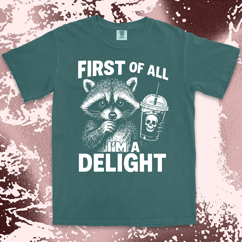 Comfort Color t-shirt with raccoon holding a spooky cup and bold text “First of all I’m a delight.”