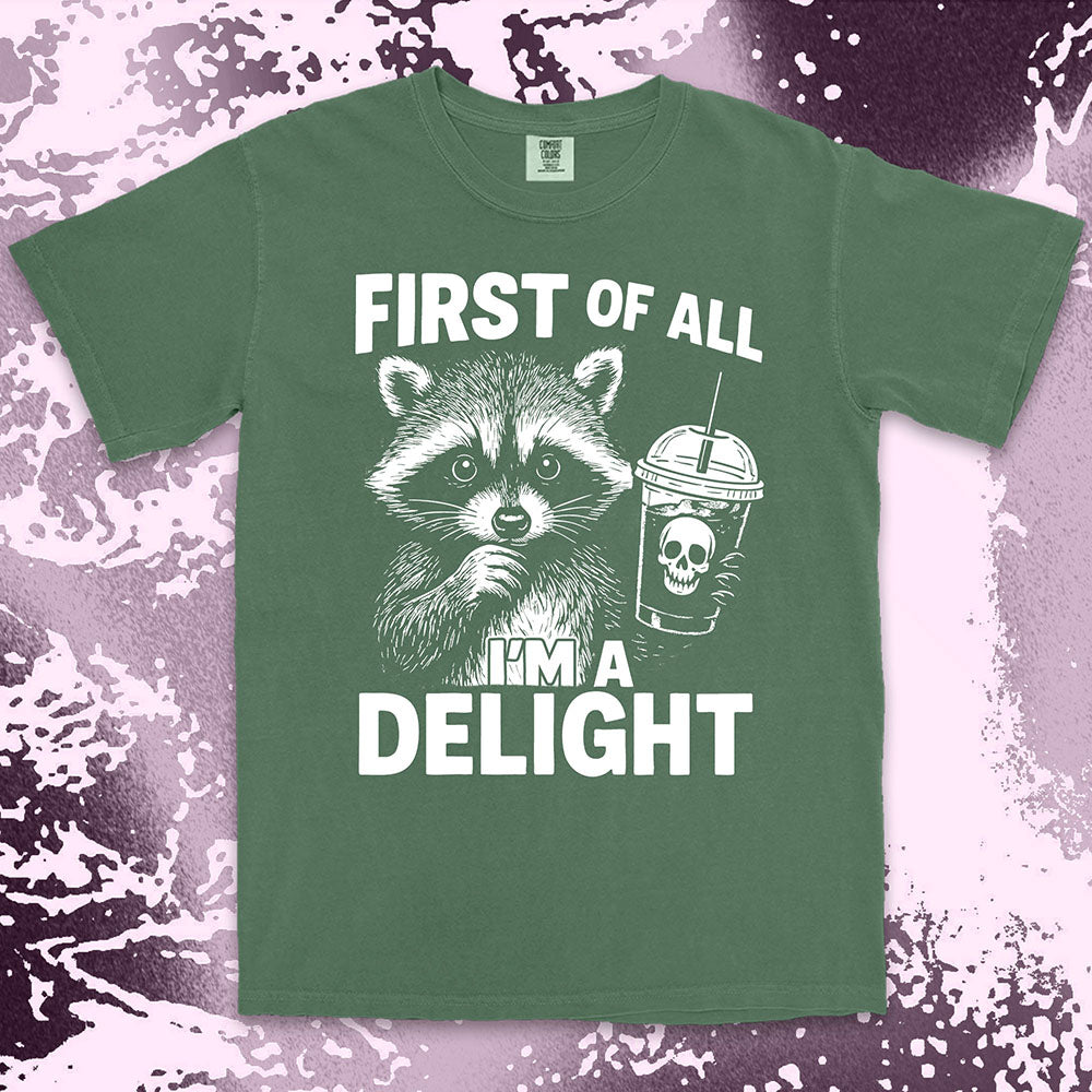 Comfort Color t-shirt with raccoon holding a spooky cup and bold text “First of all I’m a delight.”