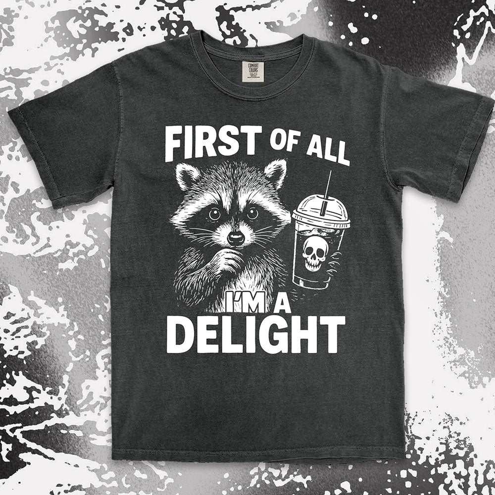 Comfort Color t-shirt with raccoon holding a spooky cup and bold text “First of all I’m a delight.”