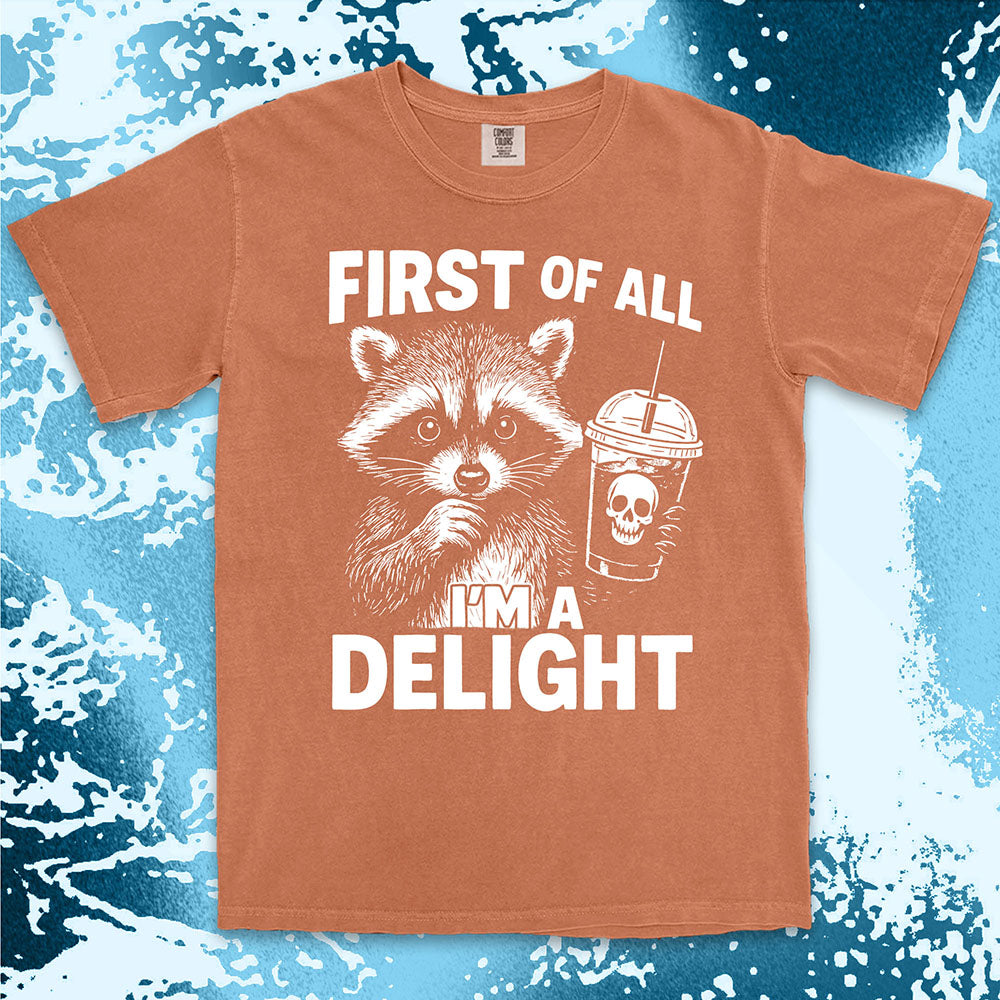 Comfort Color t-shirt with raccoon holding a spooky cup and bold text “First of all I’m a delight.”