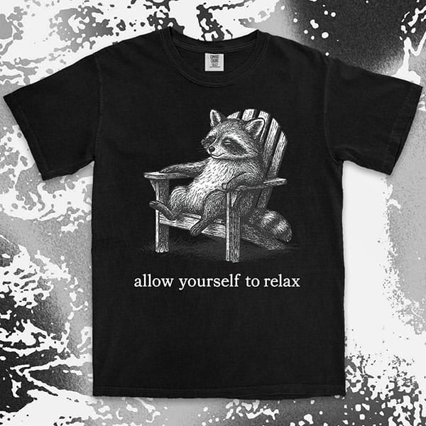 Comfort Color t-shirt with raccoon lounging on a chair and text “Allow yourself to relax” in a calm design.