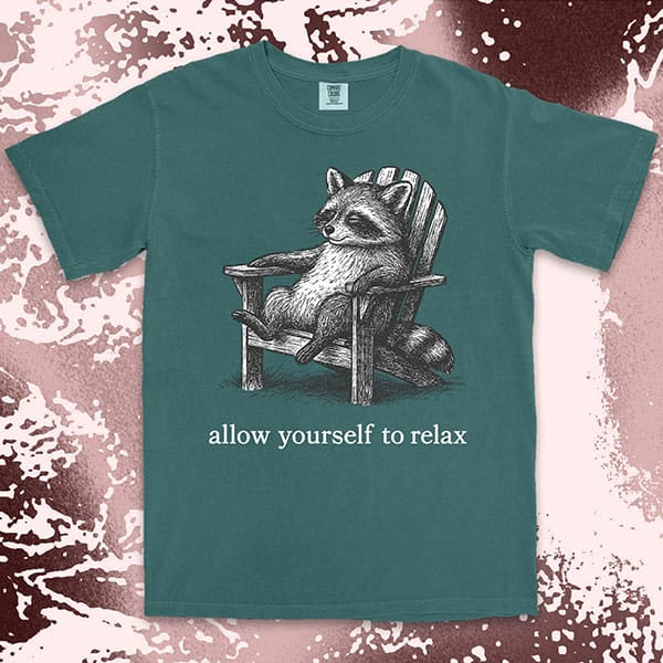 Comfort Color t-shirt with raccoon lounging on a chair and text “Allow yourself to relax” in a calm design.
