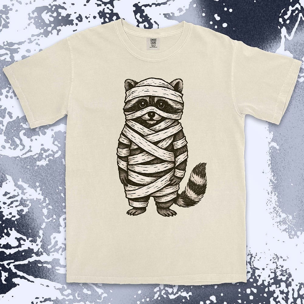 Comfort Color t-shirt with raccoon dressed as a mummy wrapped in bandages for Halloween.