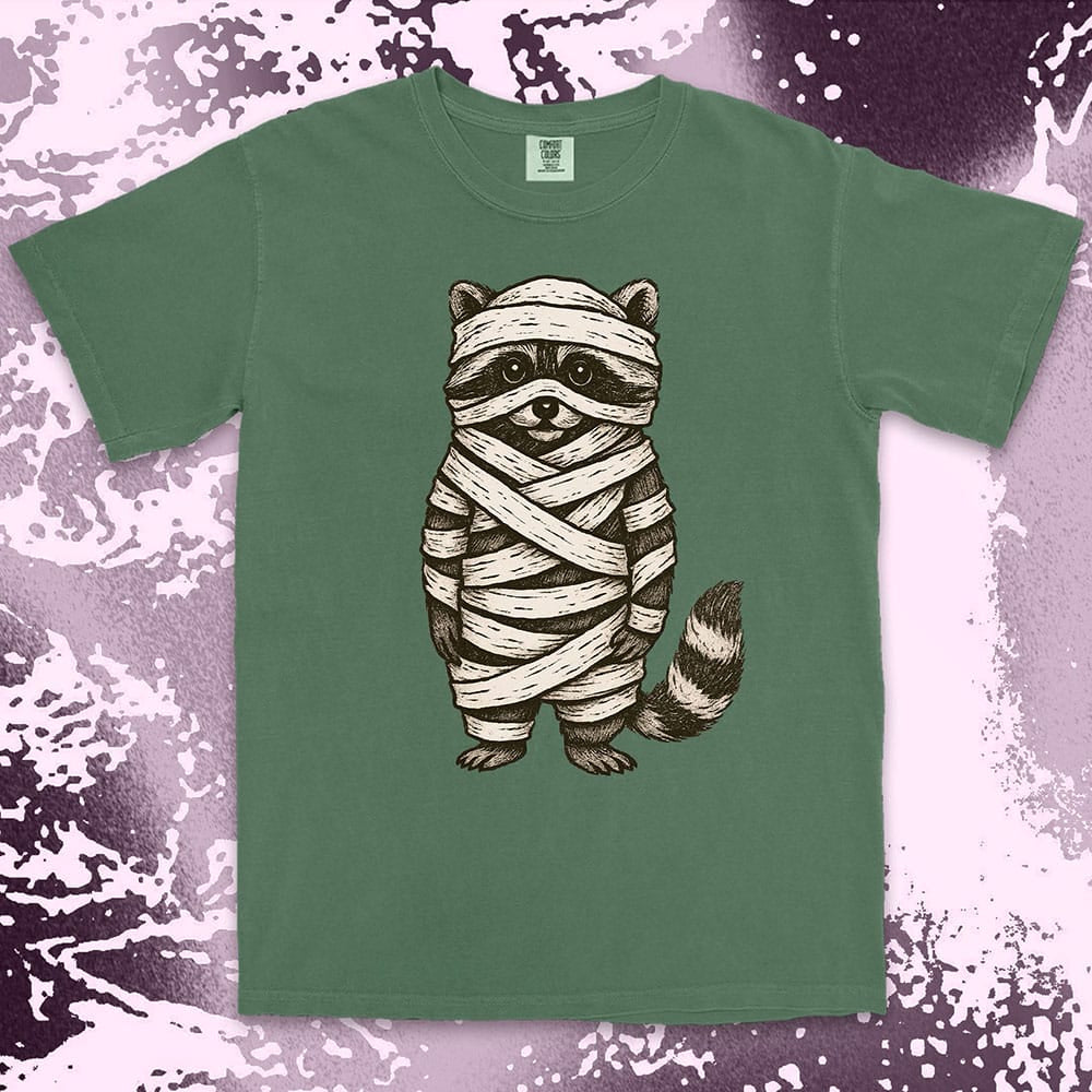 Comfort Color t-shirt with raccoon dressed as a mummy wrapped in bandages for Halloween.