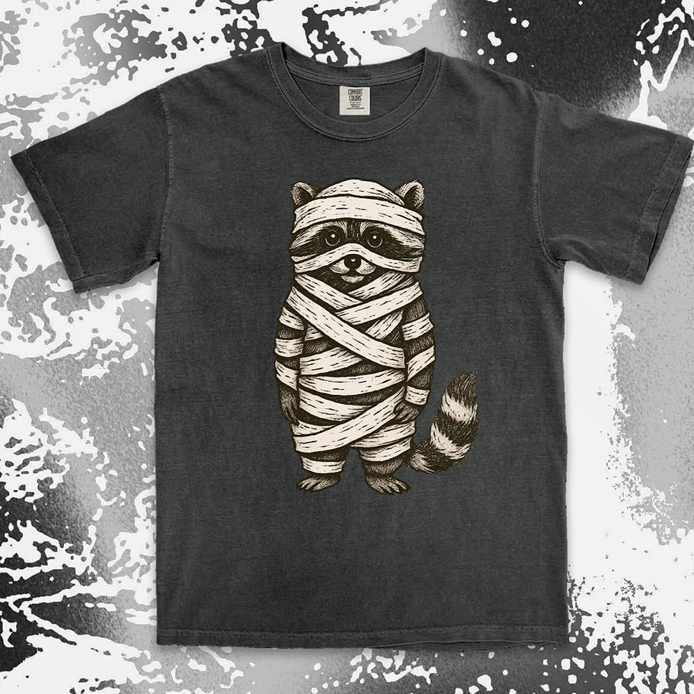 Comfort Color t-shirt with raccoon dressed as a mummy wrapped in bandages for Halloween.