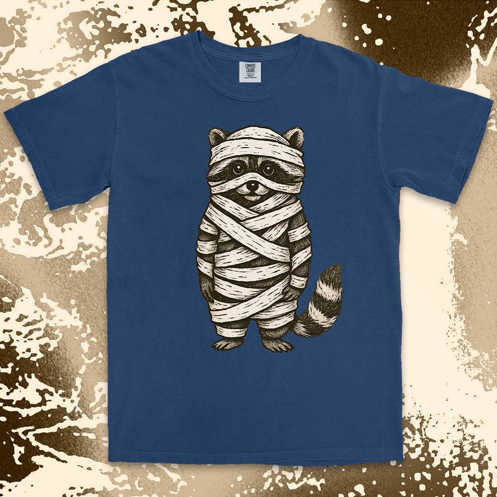 Comfort Color t-shirt with raccoon dressed as a mummy wrapped in bandages for Halloween.