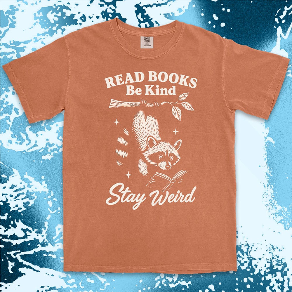 Comfort Color t-shirt with raccoon hanging from a branch reading a book and quote ÒRead books be kind stay weirdÓ printed in vintage style.