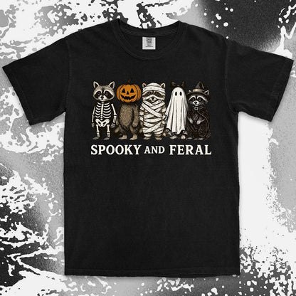 Comfort Color t-shirt with five raccoons in Halloween costumes (skeleton, pumpkin, mummy, ghost, witch) and text “Spooky and Feral.”