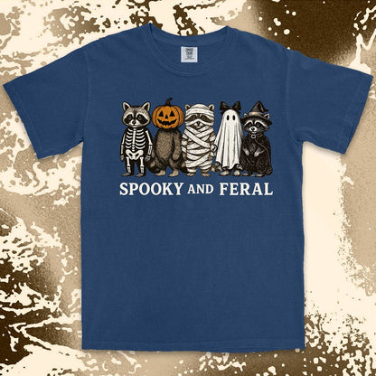 Comfort Color t-shirt with five raccoons in Halloween costumes (skeleton, pumpkin, mummy, ghost, witch) and text “Spooky and Feral.”