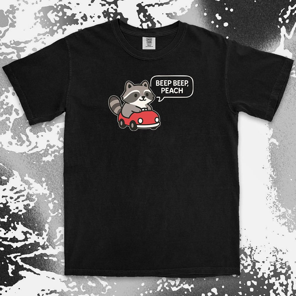 Comfort Color t-shirt with cute chibi raccoon driving a red car and speech bubble saying “Beep beep, peach.”