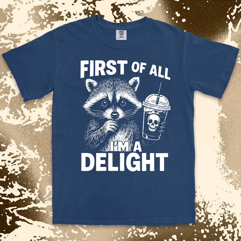 Comfort Color t-shirt with raccoon holding a spooky cup and bold text “First of all I’m a delight.”