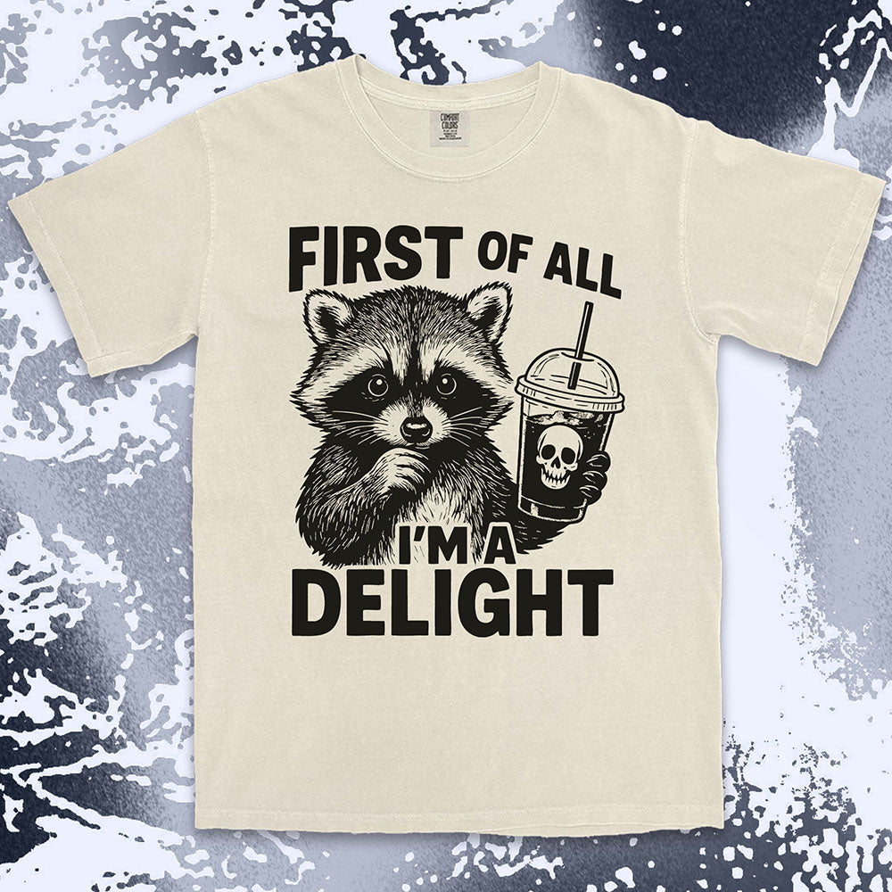 Comfort Color t-shirt with raccoon holding a spooky cup and bold text “First of all I’m a delight.”