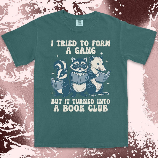 Comfort Color t-shirt with raccoon, skunk, and possum reading books and quote “I tried to form a gang but it turned into a book club.”