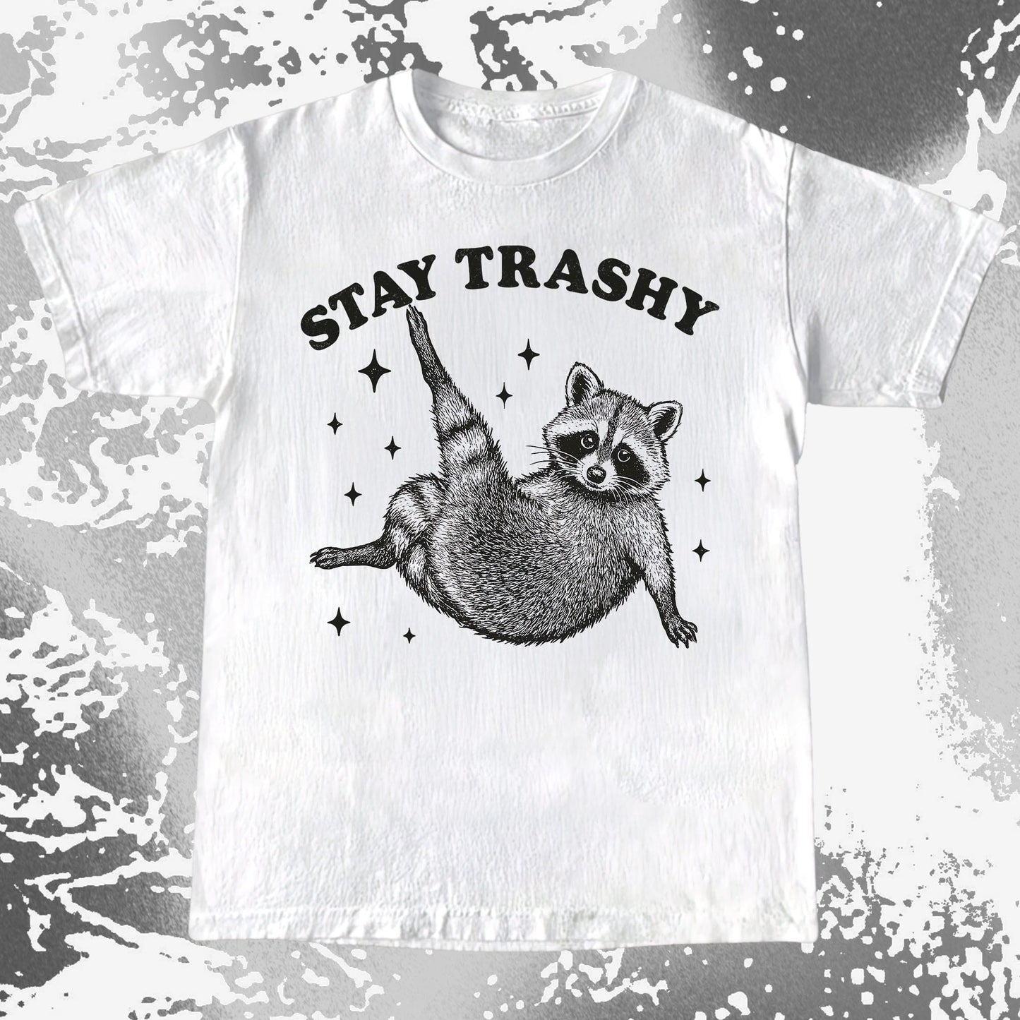 Illustration of a raccoon posing playfully with the text Stay Trashy surrounded by sparkles on a humorous T-shirt design.