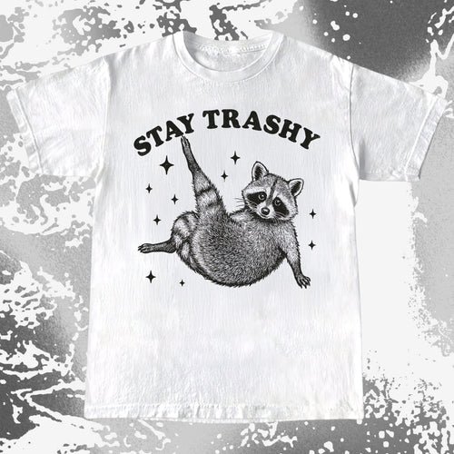 Illustration of a raccoon posing playfully with the text Stay Trashy surrounded by sparkles on a humorous T-shirt design.