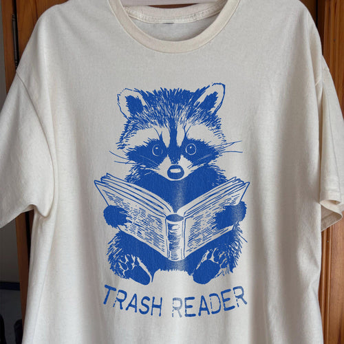 Blue raccoon illustration reading a book with the text Trash Reader in a funny book lover design