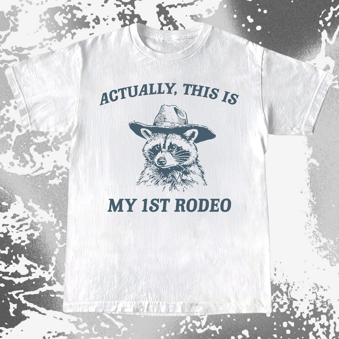 Raccoon wearing a cowboy hat with the text Actually This Is My 1st Rodeo on a humorous T-shirt design.