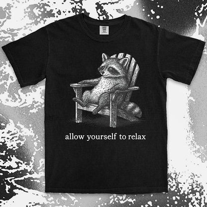 Comfort Color t-shirt with raccoon lounging on a chair and text “Allow yourself to relax” in a calm design.