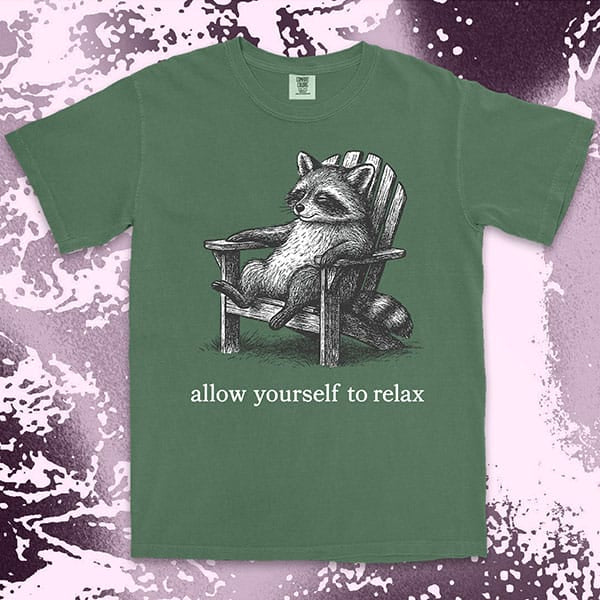Comfort Color t-shirt with raccoon lounging on a chair and text “Allow yourself to relax” in a calm design.