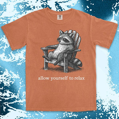 Comfort Color t-shirt with raccoon lounging on a chair and text “Allow yourself to relax” in a calm design.