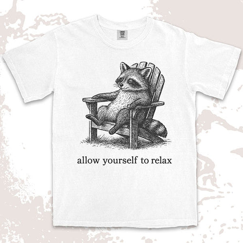 Comfort Color t-shirt with raccoon lounging on a chair and text “Allow yourself to relax” in a calm design.