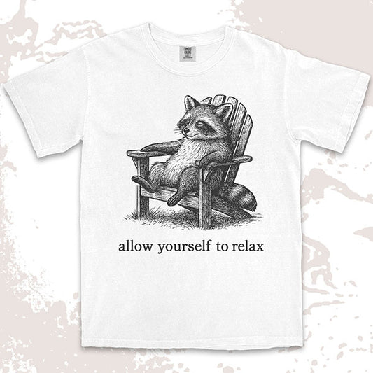 Comfort Color t-shirt with raccoon lounging on a chair and text “Allow yourself to relax” in a calm design.