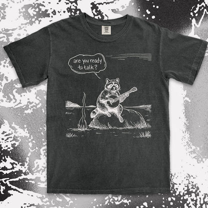 Comfort Color t-shirt with raccoon playing banjo by campfire and speech bubble saying “Are you ready to talk?”