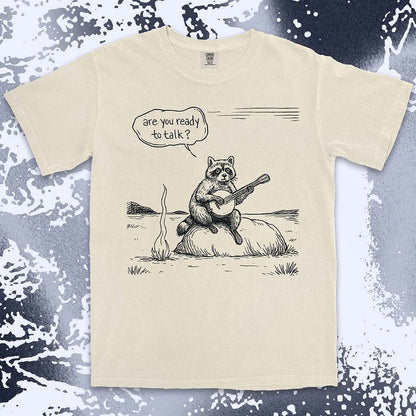 Comfort Color t-shirt with raccoon playing banjo by campfire and speech bubble saying “Are you ready to talk?”