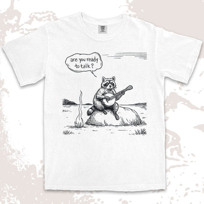 Comfort Color t-shirt with raccoon playing banjo by campfire and speech bubble saying “Are you ready to talk?”