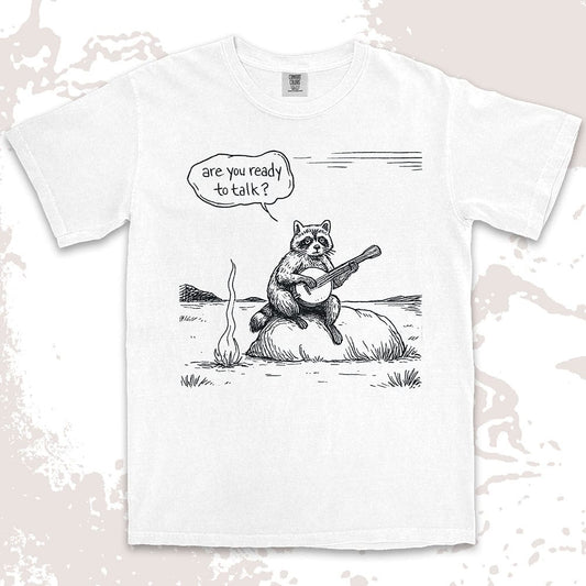 Comfort Color t-shirt with raccoon playing banjo by campfire and speech bubble saying “Are you ready to talk?”