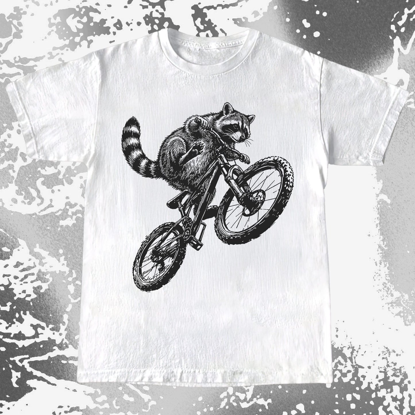White t-shirt with a black and white illustration of a raccoon riding a bicycle on a distressed background.