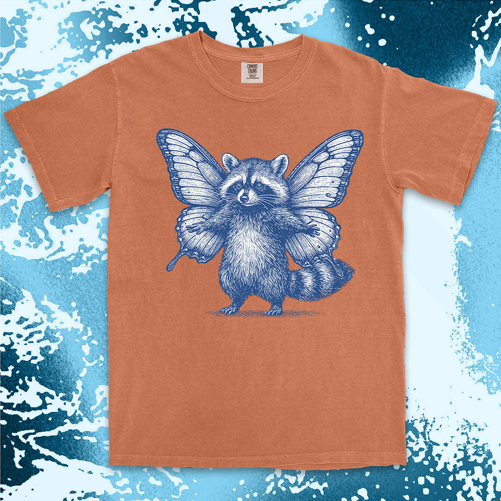 Comfort Color t-shirt with raccoon illustration featuring big butterfly wings in a magical fairy style.