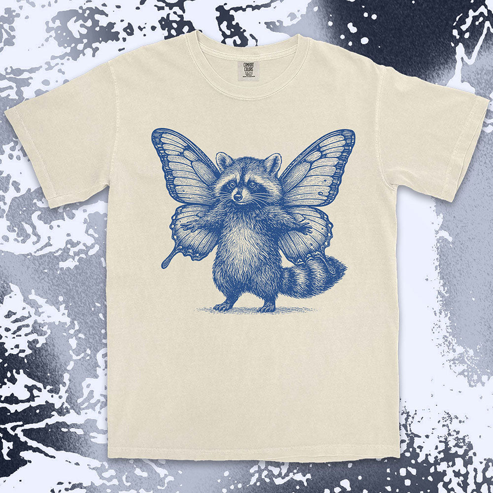 Comfort Color t-shirt with raccoon illustration featuring big butterfly wings in a magical fairy style.
