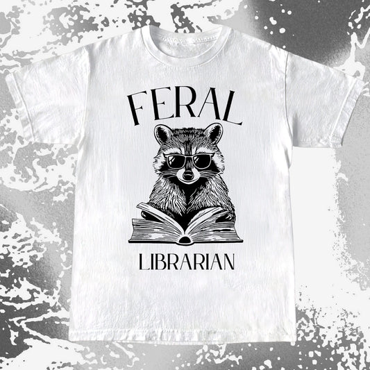 Raccoon wearing sunglasses reading a book with the text Feral Librarian vintage illustration