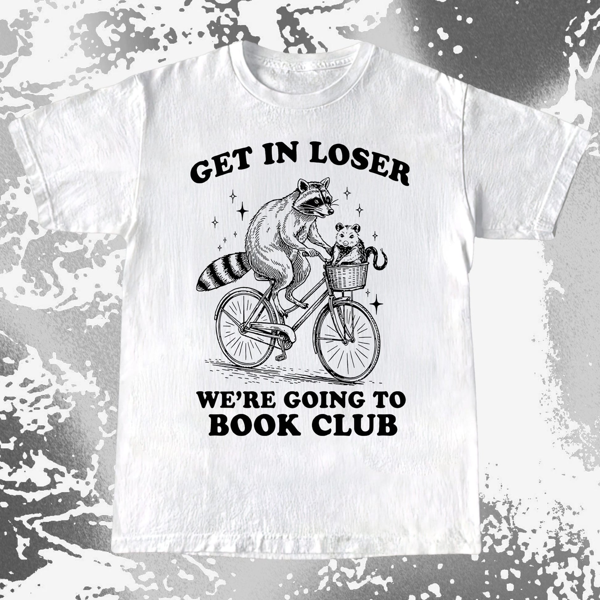 Raccoon riding a bicycle with an opossum in a basket and the text “Get In Loser, We’re Going to Book Club” on a humorous T-shirt design.