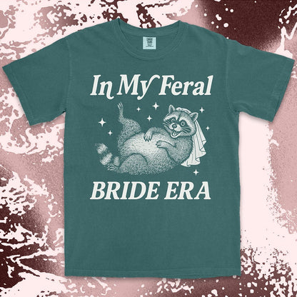 Comfort Color t-shirt with a raccoon wearing a bridal veil and text ÒIn My Feral Bride EraÓ in playful vintage lettering.