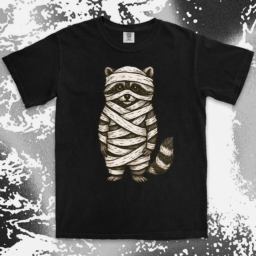 Comfort Color t-shirt with raccoon dressed as a mummy wrapped in bandages for Halloween.