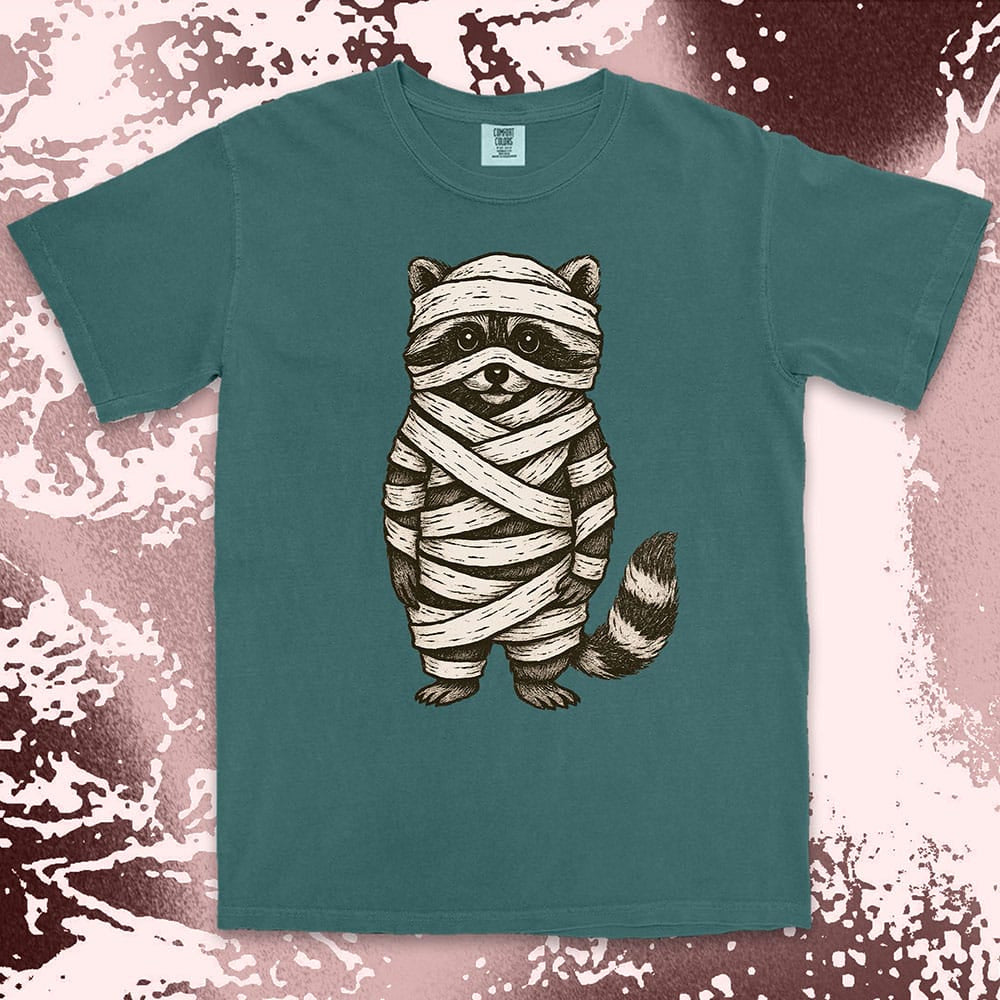Comfort Color t-shirt with raccoon dressed as a mummy wrapped in bandages for Halloween.