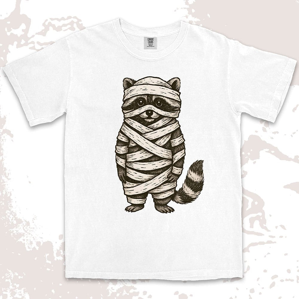 Comfort Color t-shirt with raccoon dressed as a mummy wrapped in bandages for Halloween.