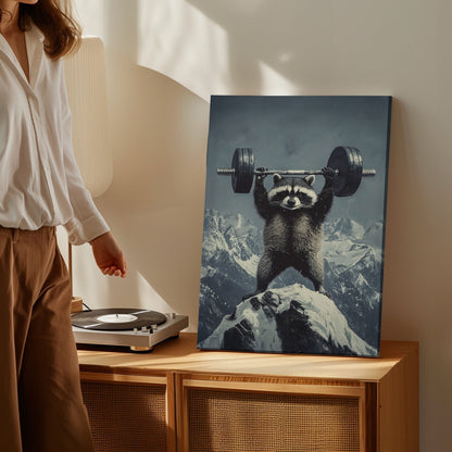 Feral raccoon lifting weights canvas wall art featuring a raccoon holding a barbell on snowy mountain peak in motivational funny style