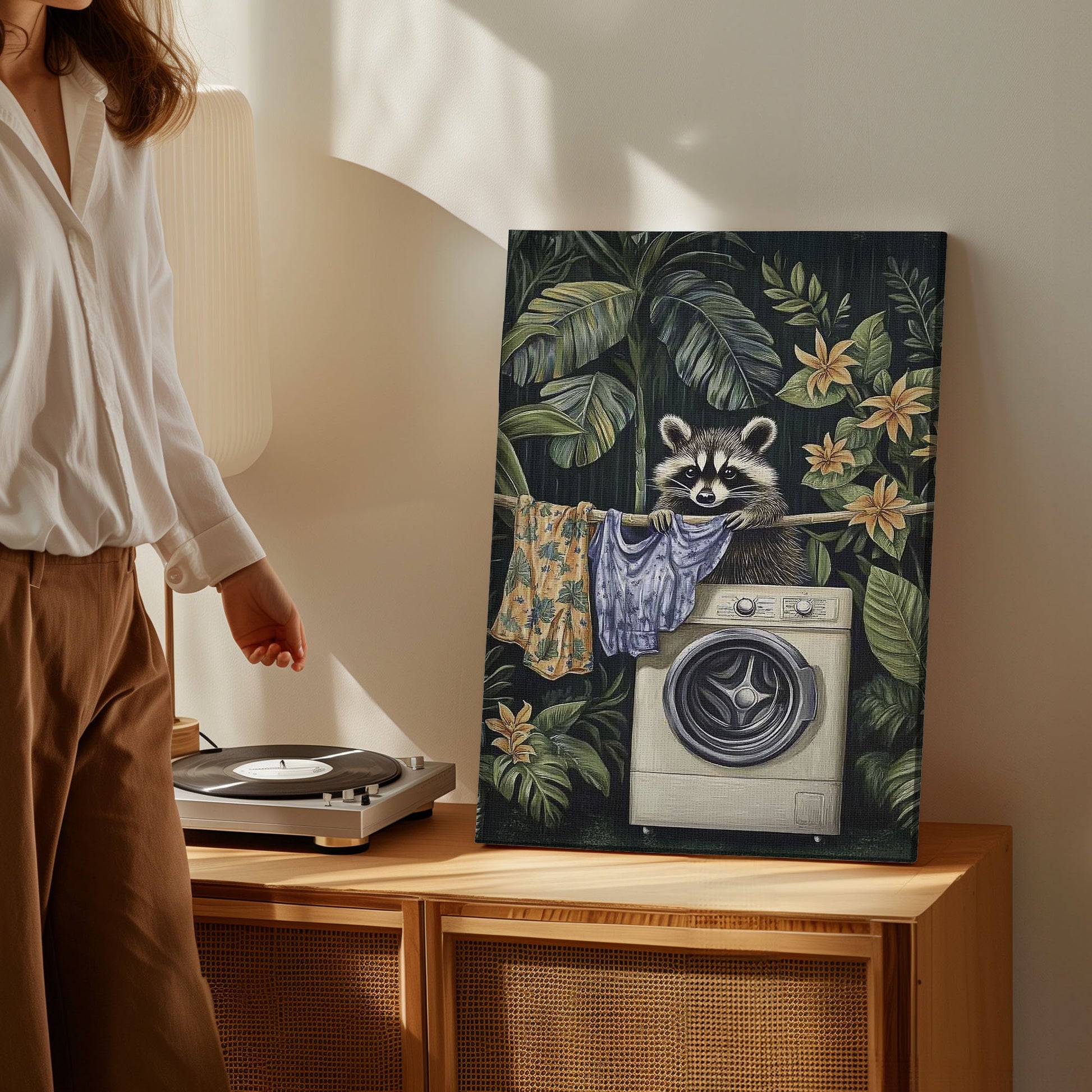 Laundry raccoon canvas wall art featuring a raccoon with washing machine and hanging clothes among green tropical plants and yellow flowers