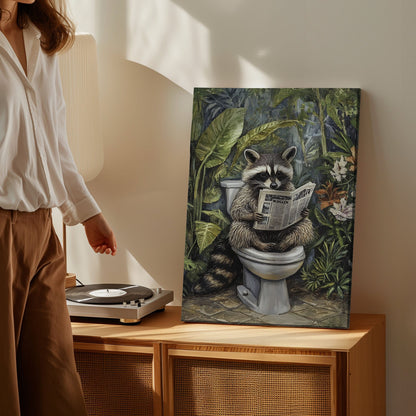 Bathroom raccoon canvas wall art featuring a raccoon sitting on toilet reading a newspaper surrounded by green tropical plants