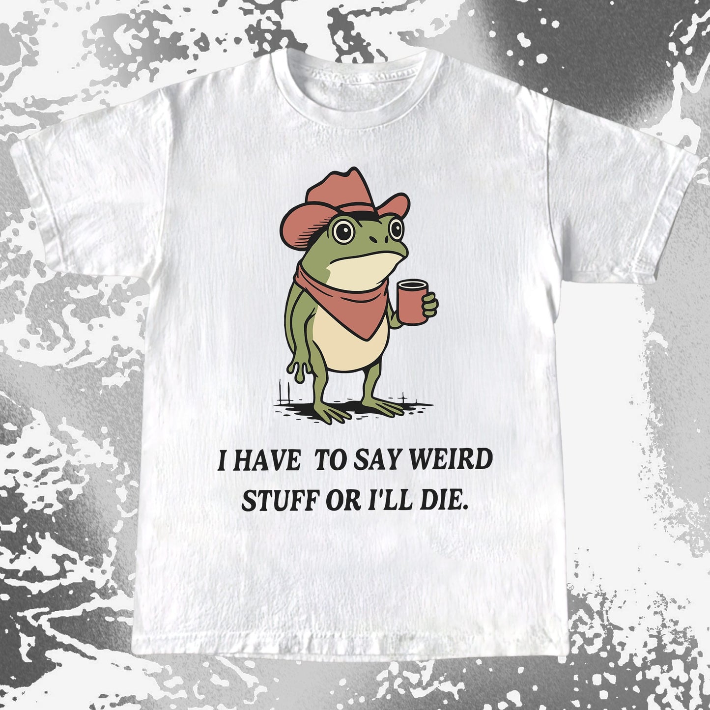 White t-shirt with a cartoon frog wearing a cowboy hat and scarf, holding a coffee cup, and text 'I HAVE TO SAY WEIRD STUFF OR I'LL DIE.' on a distressed gray background.