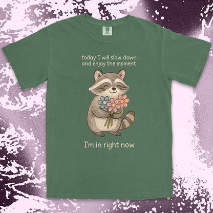 Comfort Color t-shirt with a smiling raccoon holding flowers and text ÒToday I will slow down and enjoy the moment Ð IÕm in right nowÓ in a soft, mindful design.