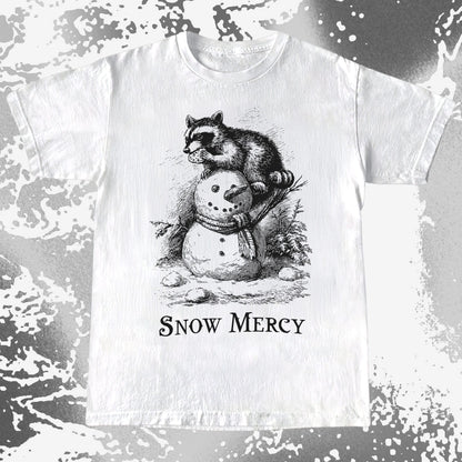 White t-shirt with a graphic of a raccoon on a snowman and 'Snow Mercy' text, against a distressed white and gray background.