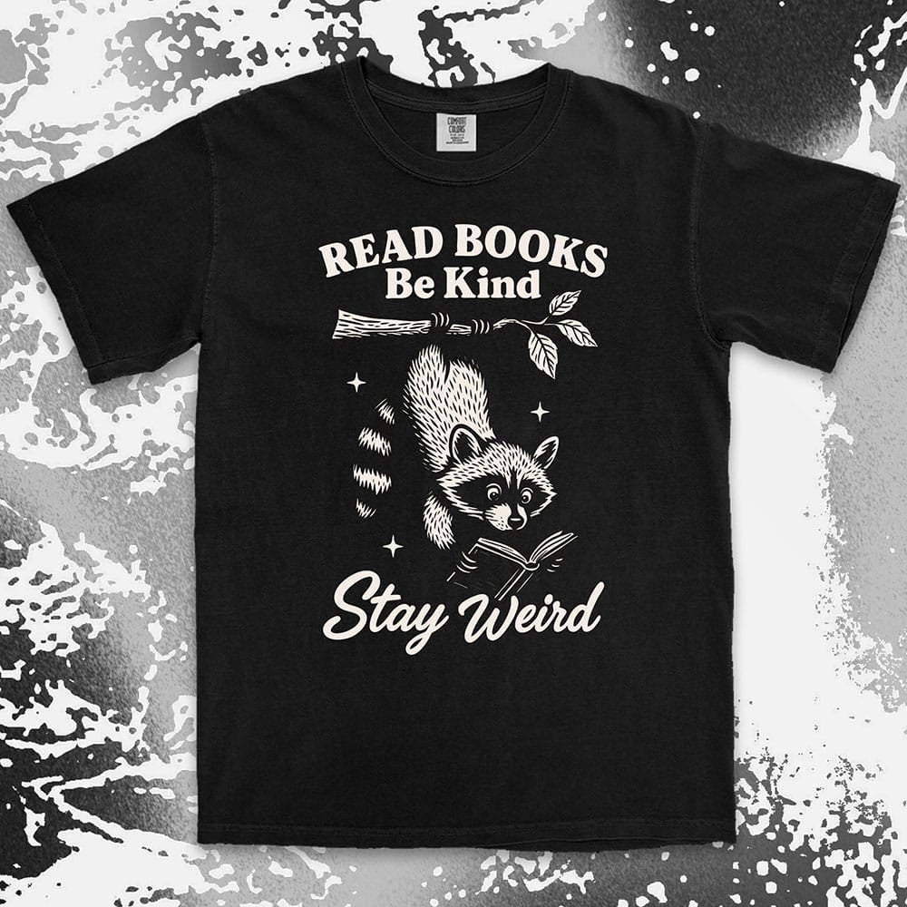 Comfort Color t-shirt with raccoon hanging from a branch reading a book and quote ÒRead books be kind stay weirdÓ printed in vintage style.